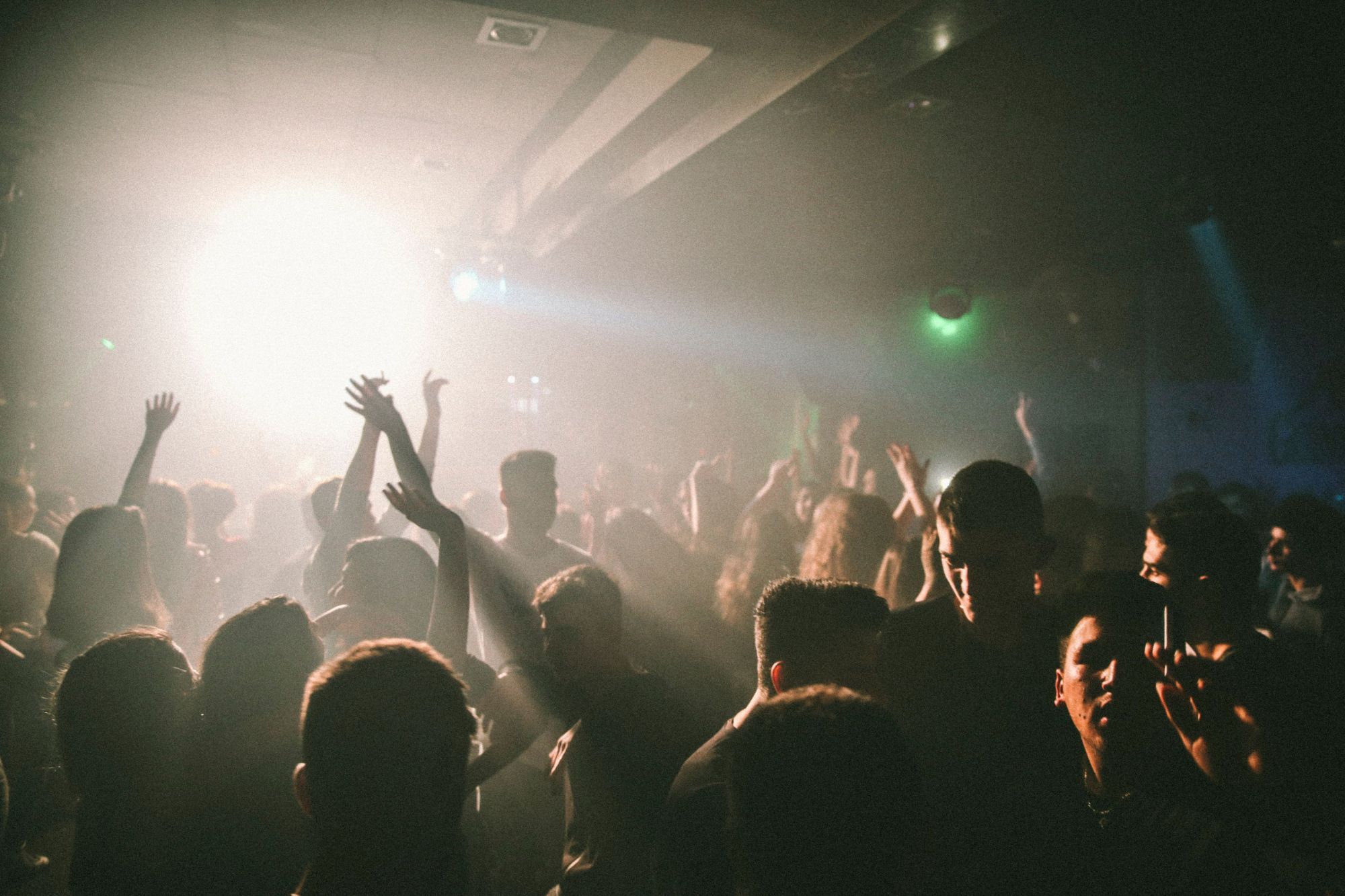 A packed dancefloor, hands up, lit through smoke.