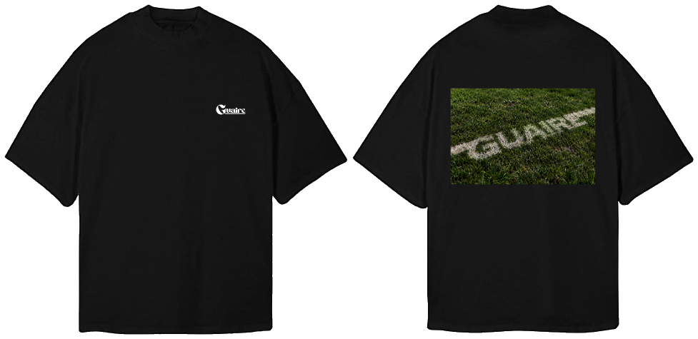 Black oversized tee, front and back: a small white Guaire logo on the chest and a photo of GUAIRE painted as a white line on pitch grass across the back.